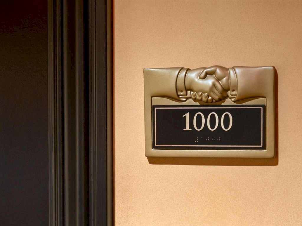 A safe-style wall panel shows &ldquo;1000&rdquo; with a metallic handshake icon above a dark display window.