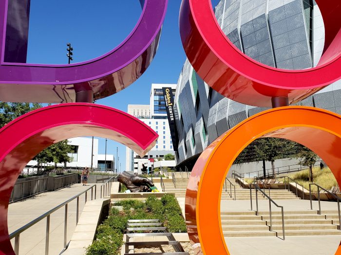 Colorful giant rings frame a plaza outside the Google Innovation Center, with stairs, railings, and modern buildings behind.
